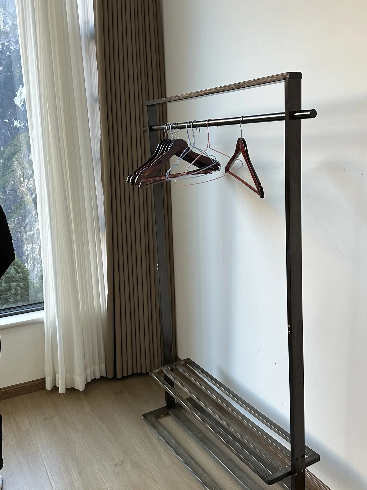 A bare clothes rack by the window, part of the room's sparse fit-out