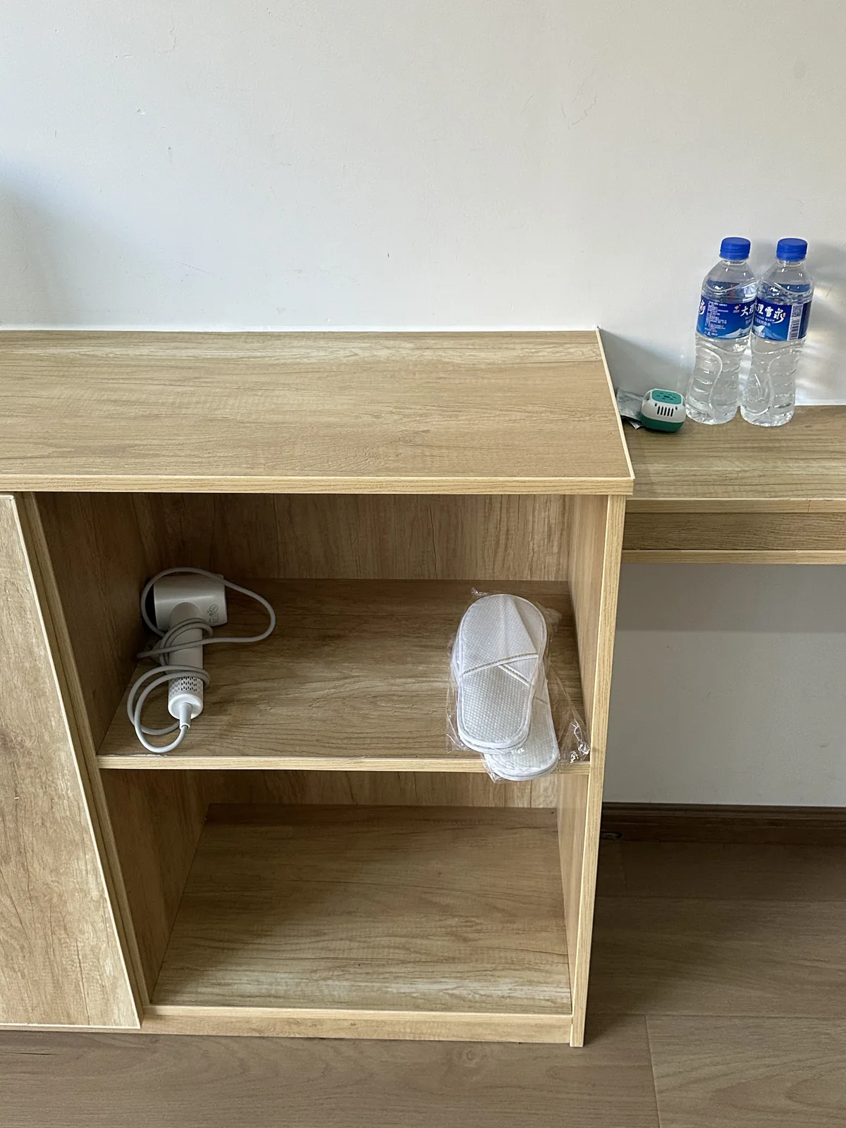 Open shelving with bottled water, a hair dryer and slippers